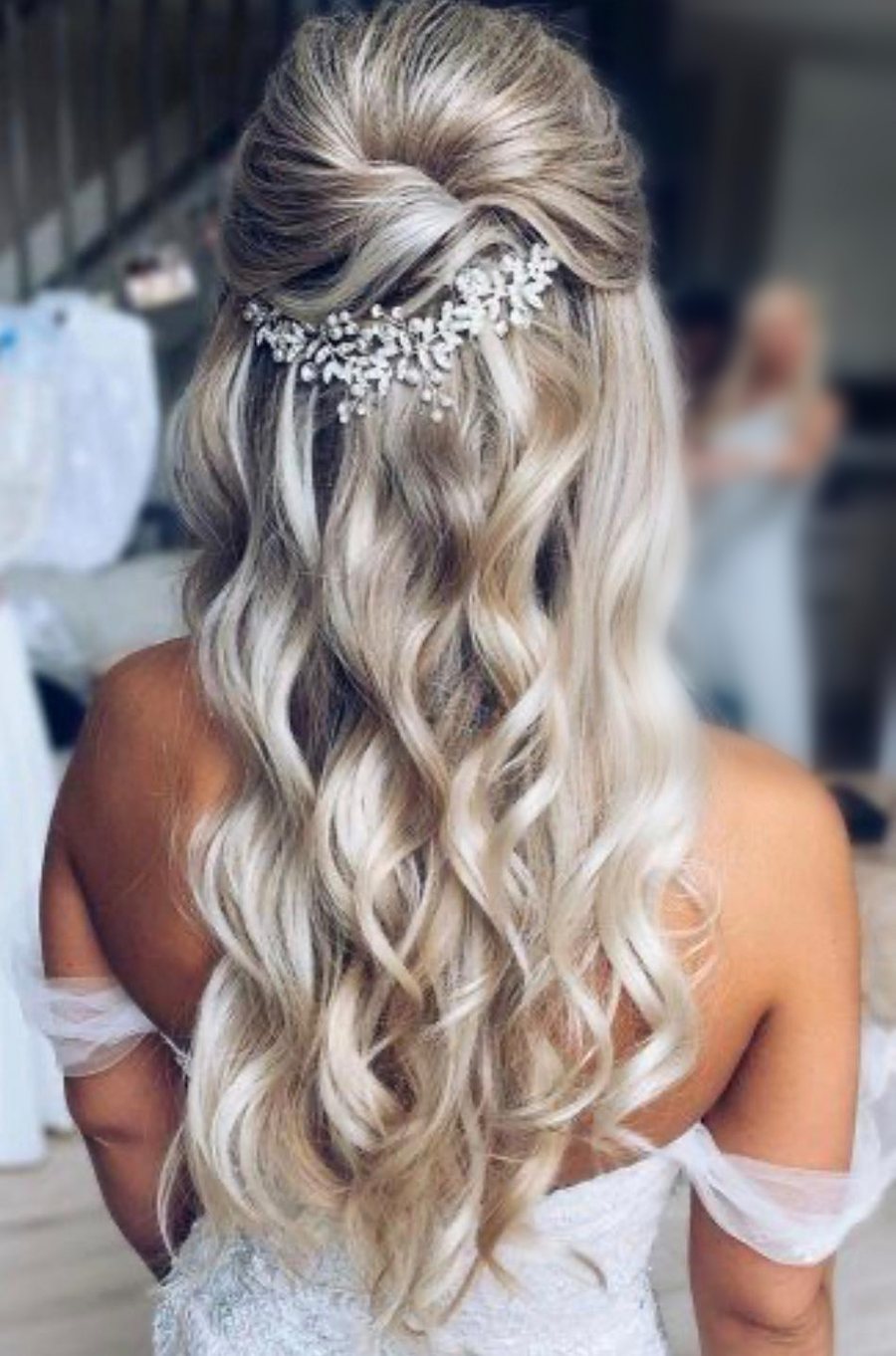 A half-up bridal style with soft waves and a pearl hairpiece